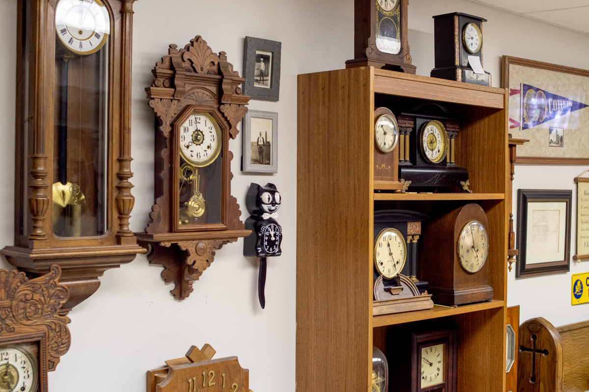 a variety of clocks arranged on a wall with shelves