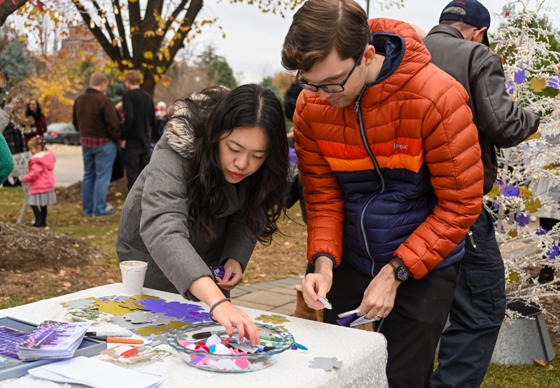 A woman and a man decorate angel ornaments at the Tree of Life