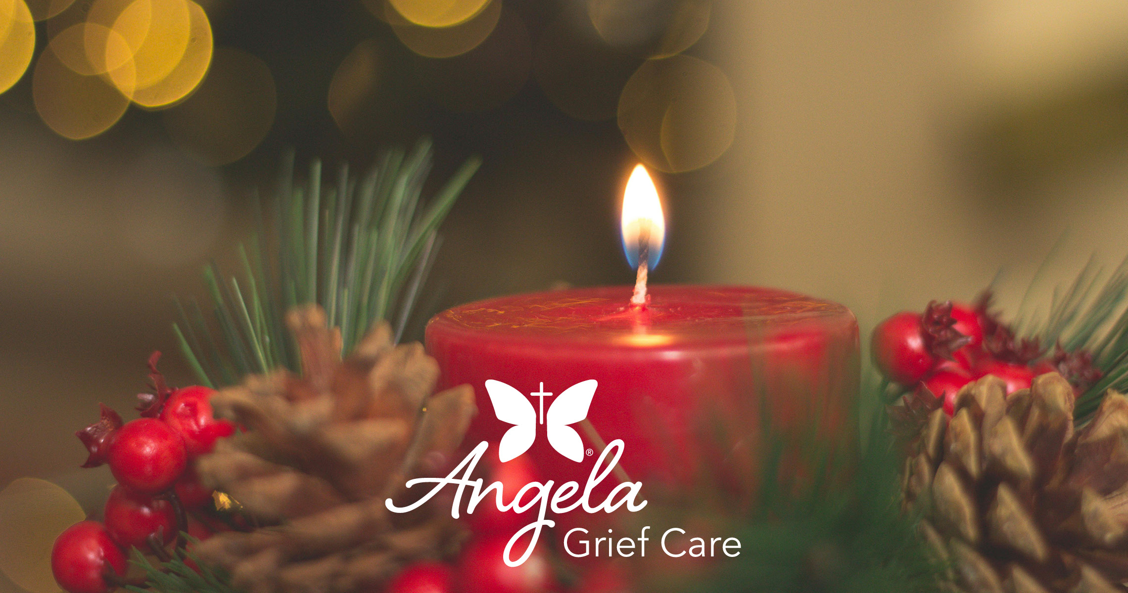 a red candle with pine cone and greenery